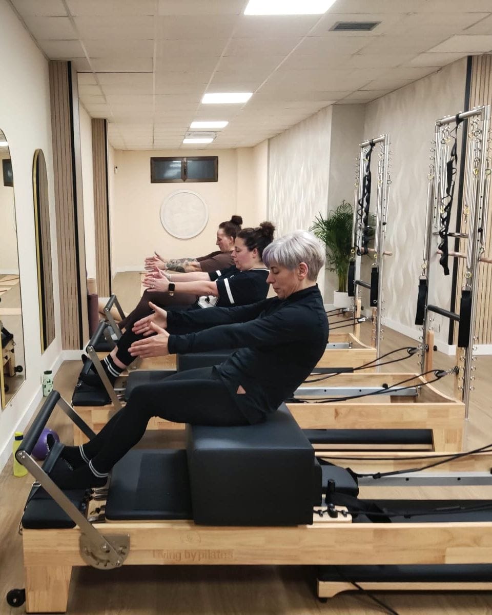 Tres alumnas trabajando sobre las máquinas reformer del estudio, frente a los espejos de arco.