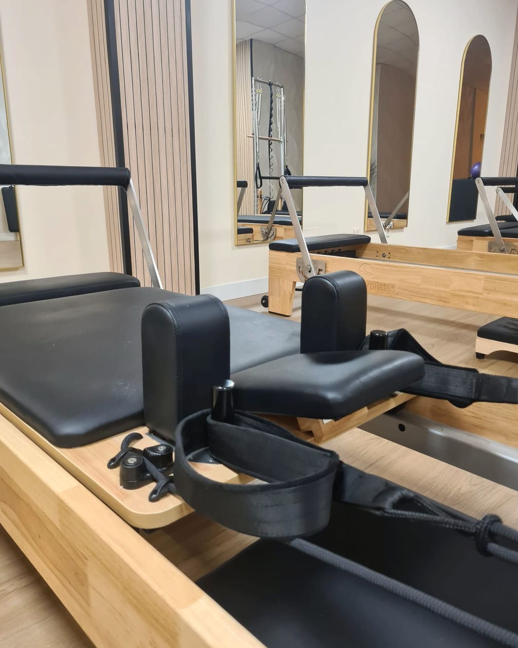 Detalle de una máquina reformer: la madera clara, la tapicería negra y las correas.